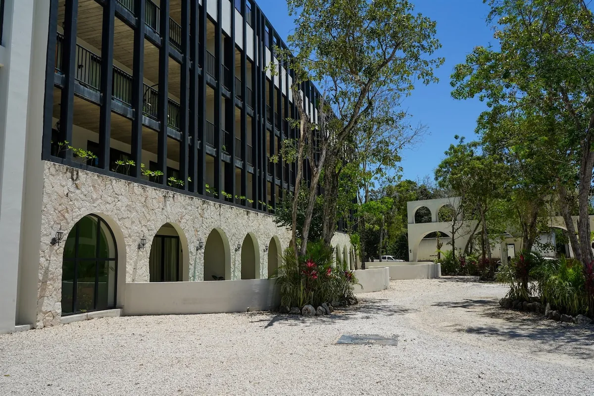 Fachada de piedra con arcos y camino de grava del conjunto Tuk Tulum, en el centro de Tulum