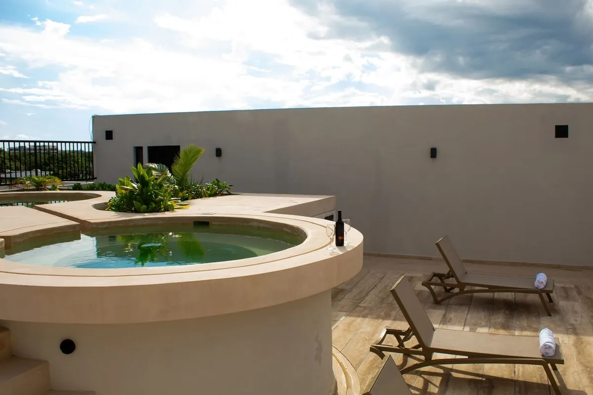 Azotea del conjunto con jacuzzi circular y camastros, en el centro de Tulum