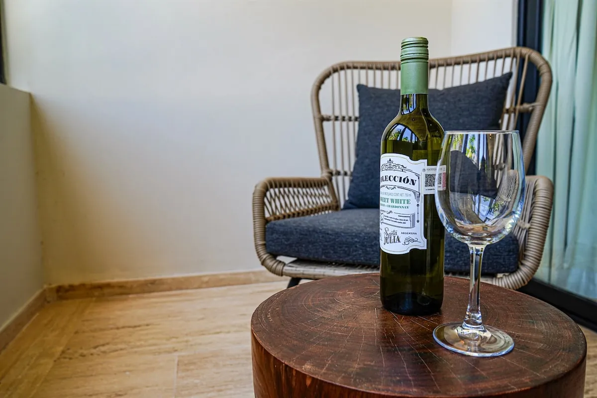Rincón de la terraza con sillón de mimbre, botella de vino y dos copas