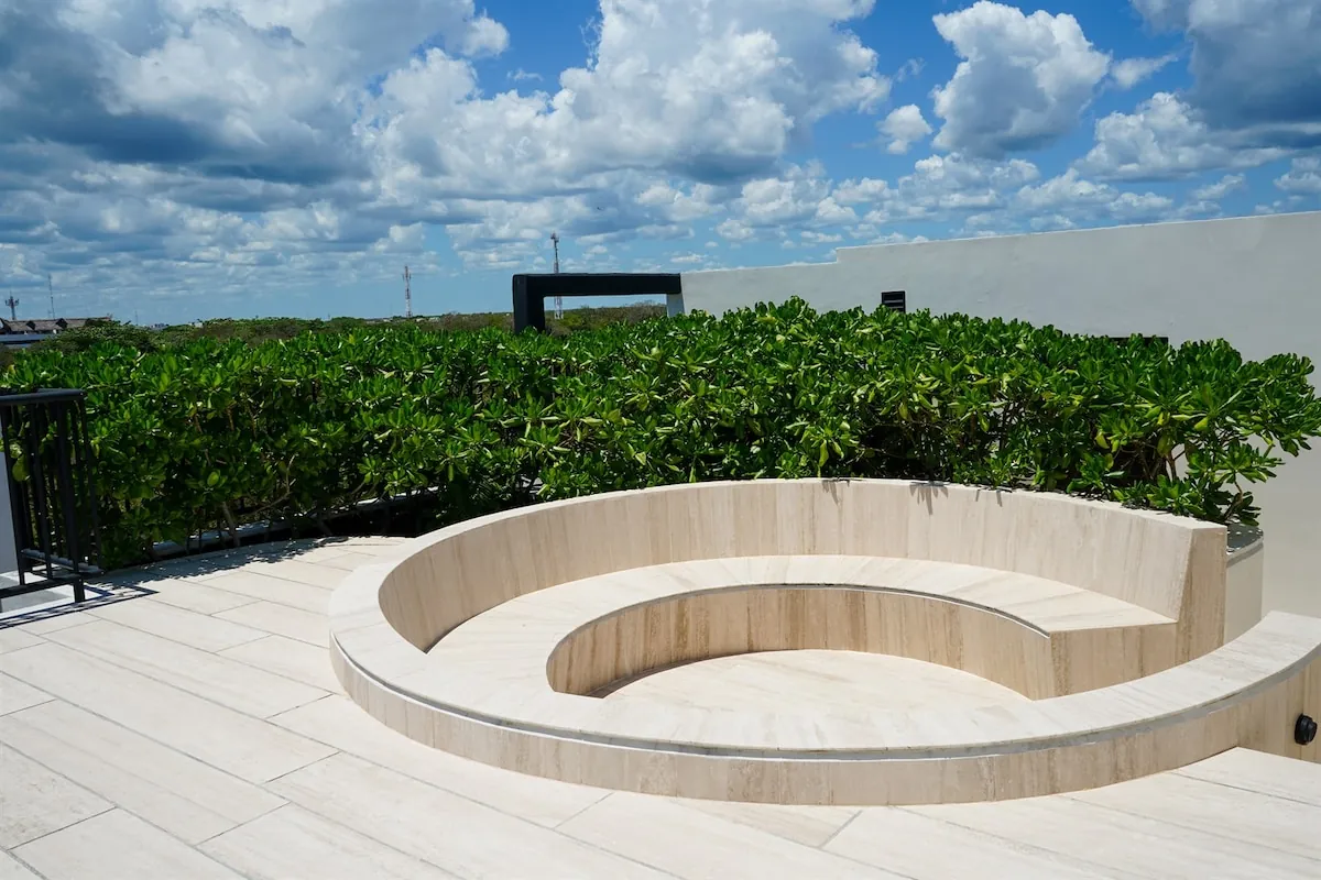 Banca curva de piedra en la azotea del conjunto, con la selva de Tulum de fondo