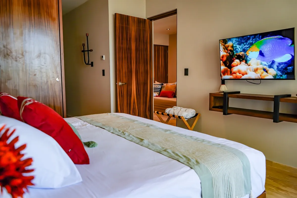 Segunda recámara con cama doble, televisión y cojines rojos