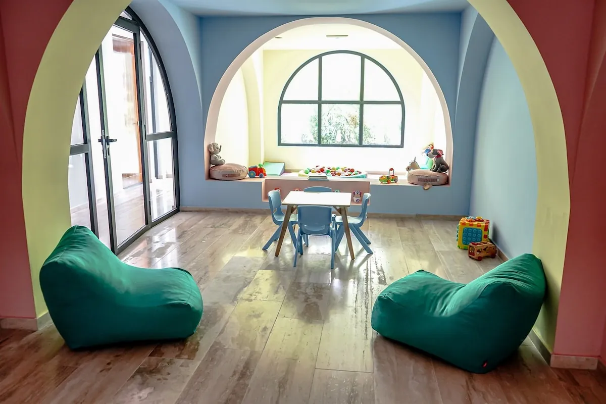 Zona común con arco pintado, pufs verdes y mesa infantil
