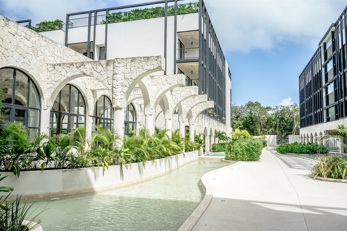 Arcos de piedra y espejo de agua en el patio del Tuk Tulum Art Walk