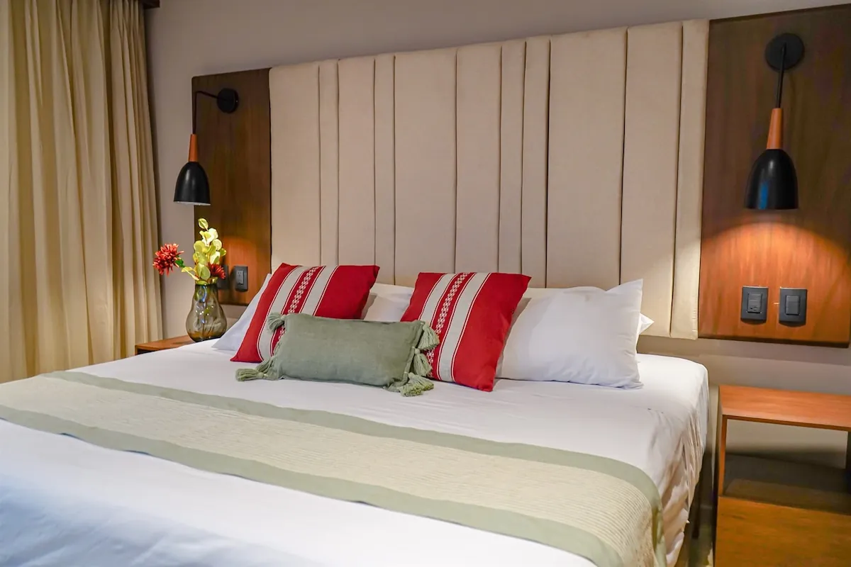 Recámara con cama doble y cojines verdes y rojos