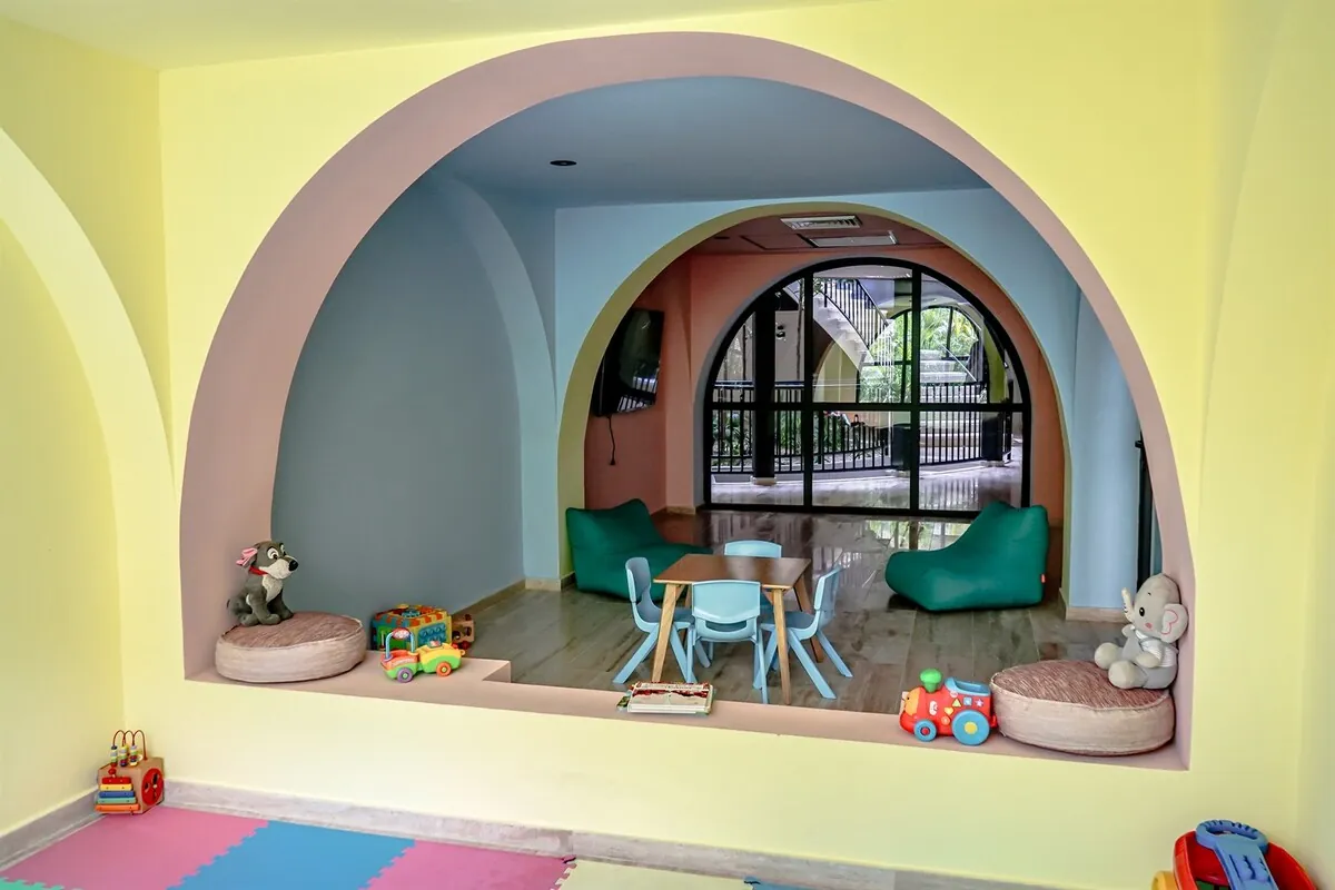 Zona de juegos infantiles con arco pintado, mesa pequeña y juguetes