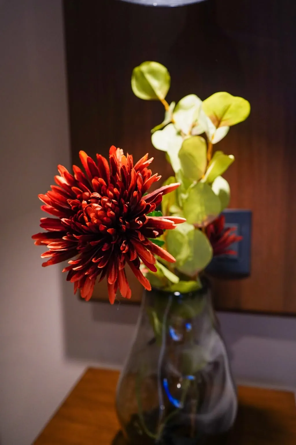 Jarrón con flores rojas y una orquídea sobre una mesa del departamento