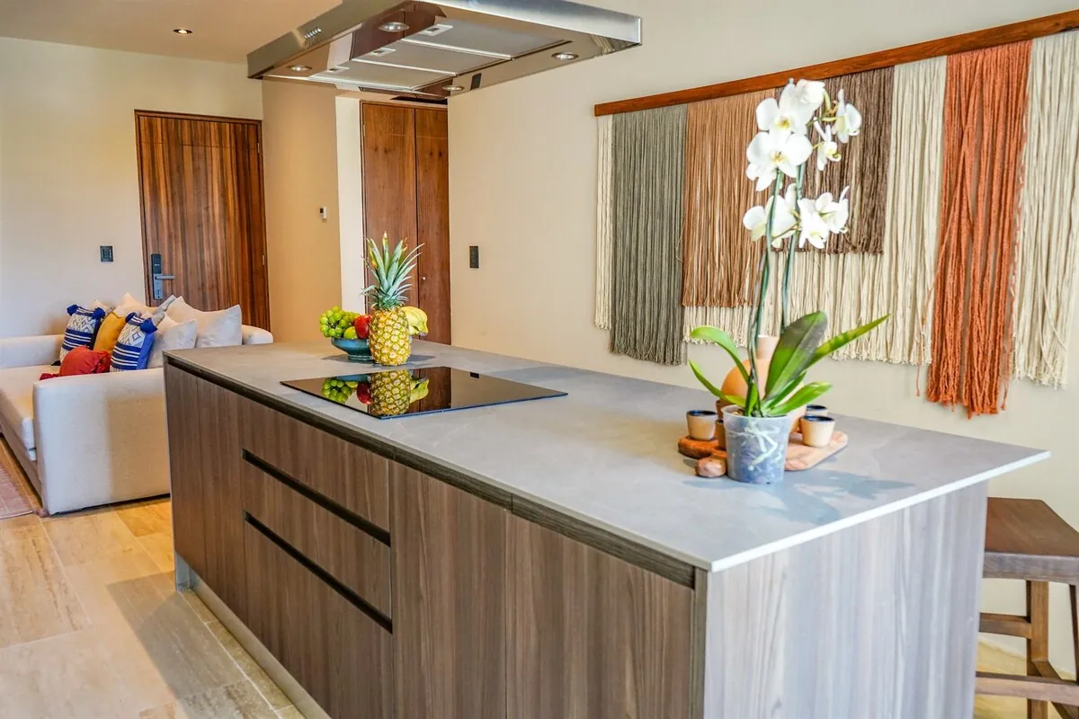 Cocina con isla de mármol, campana de acero y orquídeas